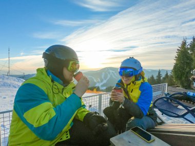 Çift tepenin üstünde dinleniyor ve sıcak çay içiyor. Snowboard kayak yaşam tarzı