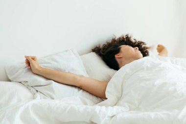 Genç ve güzel bir kadın beyaz çarşaflı parlak ışık fotokopi alanı