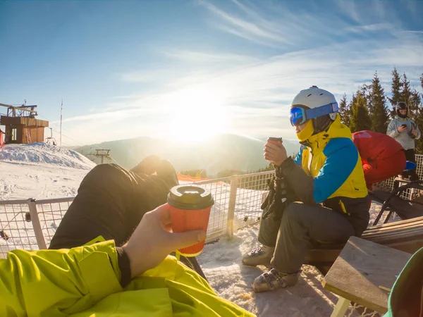 Karlı tepenin tepesinde dinlenen bir çift çay içiyor. Snowboard ve kayak. kış ekstrem spor