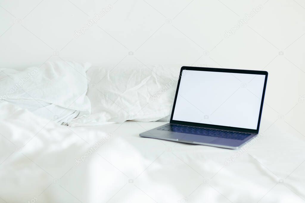 laptop with copy space empty screen at bed with white sheets nobody
