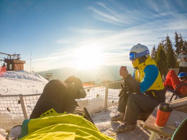 Karlı tepenin tepesinde dinlenen bir çift çay içiyor. Snowboard ve kayak. kış ekstrem spor