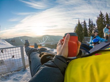 Kışın tepesinde gün batımında manzaralı sıcak çay içen bir kadın. kayak ve snowboard yaşam tarzı