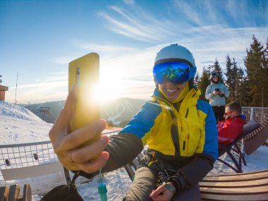 Kayak ekipmanlı bir kadın, gün batımında karlı dağlarda selfie çekiyor. spor yaşam tarzı