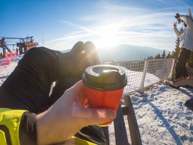 Adam kış tepesinde gün batımında manzaralı çay içiyor. kopyalama alanı. snowboard sporu