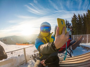 Kayak ekipmanlı bir kadın, gün batımında karlı dağlarda selfie çekiyor. spor yaşam tarzı