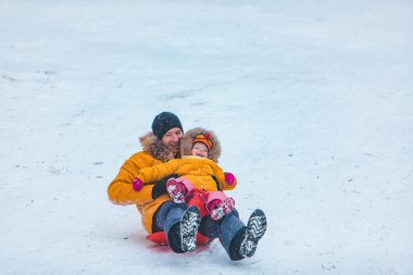Baba ve kızı sarı kışlık paltolar içinde kaygan tepe aile zamanı