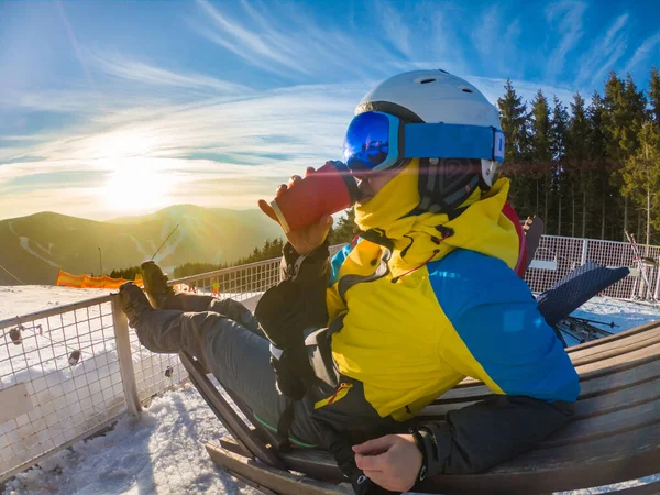 夕日を眺めながら冬の丘の上で熱いお茶を飲む女 スキーやスノーボードのライフスタイル — ストック写真
