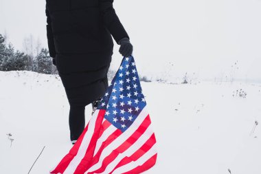 Kadın elinde ABD bayrağı ile karda yürüyordu. Kapat. Vatansever kavram