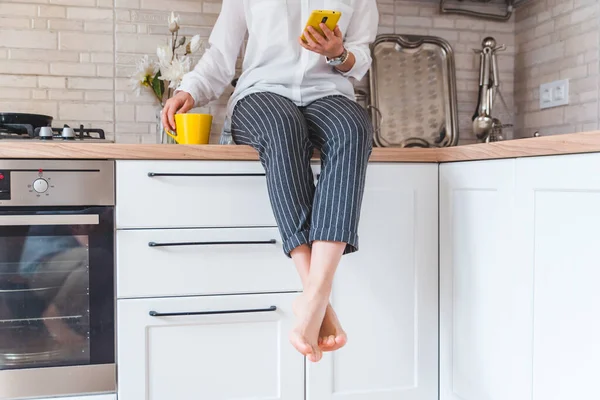 Mujer Sentada Mesa Cocina Con Teléfono Taza Amarilla Beber — Foto de Stock