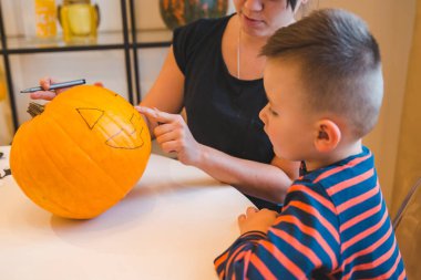 Anne oğul evde balkabağı kafası yapıyorlar. Tatil hazırlığı küçük çocuk.