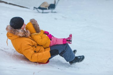 Baba ve kızı sarı kışlık paltolar içinde kaygan tepe aile zamanı
