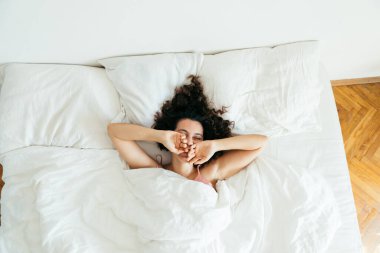 Genç ve güzel bir kadın beyaz çarşaflı parlak ışık fotokopi alanı