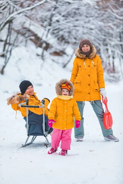 年轻的家庭在户外白雪蒙蒙的冬日里一起玩耍 黄色的外套 — 图库照片