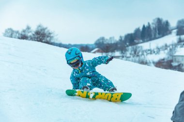 Lviv, Ukrayna - 12 Ocak 2019: küçük bir kız snowboard öğreniyor. Yat yere. çocukluk