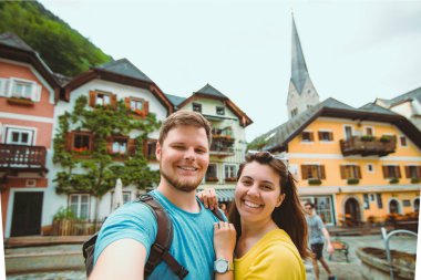 Gülümseyen sevimli çift Hallstatt City Meydanı Seyahat Konseptinde selfie çekiyor.