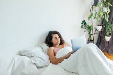 Yatakta dizüstü bilgisayarı olan kadın serbest internet alışverişi yapıyor.