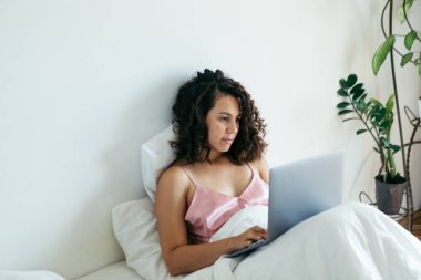 Yatakta dizüstü bilgisayarı olan kadın serbest internet alışverişi yapıyor.