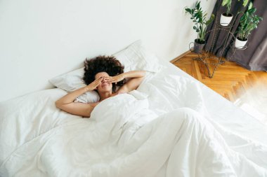 Genç ve güzel bir kadın beyaz çarşaflı parlak ışık fotokopi alanı