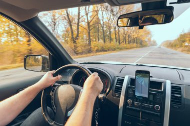 Yolculuk konsepti adamım direksiyonda ellerini sonbahar mevsiminde telefonda gezdirir.