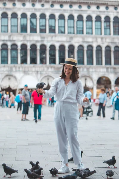 Beyaz şapkalı kadın Venice City Meydanı San Marco 'da güvercinlerle eğleniyor.