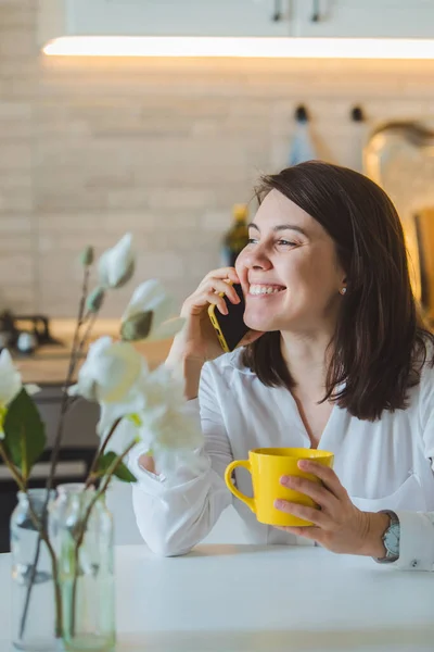 Woman Drinking Tea Yellow Mug Kitchen Talking Phone — Stock Photo, Image