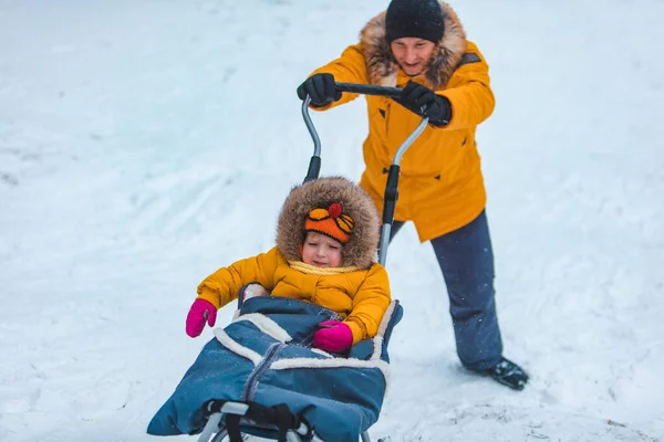 黄色い冬のコートを着た娘と一緒に雪の丘の家族の時間を滑り — ストック写真