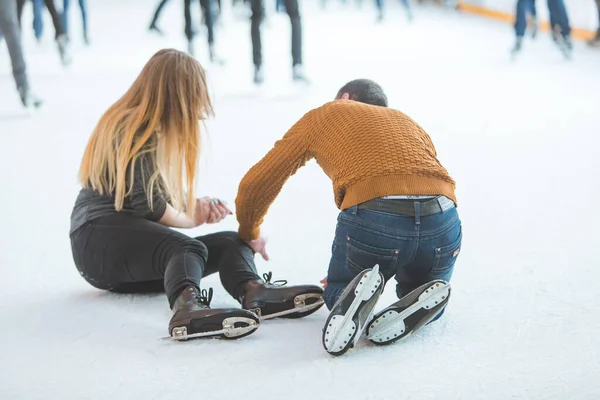 女性はスケートをしながら落ちる 男は彼女を助けます スポーツ活動 — ストック写真
