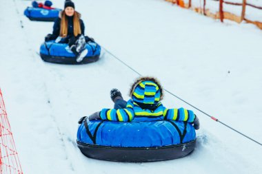 Tepeden yukarı doğru çekilen kar tüpleri. Aileler boş vakitlerinde. kış aktiviteleri
