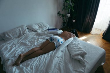woman laying on the bed white sheets light from window with curtains. copy space