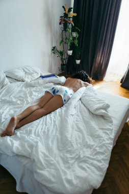 woman laying on the bed white sheets light from window with curtains. copy space