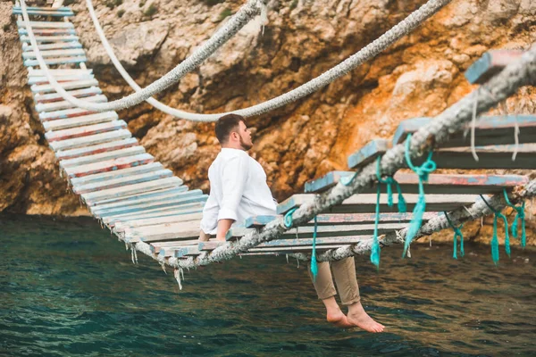 Homem Sentado Ponte Suspensa Desfrutando Vista Para Mar Natureza Calma — Fotografia de Stock