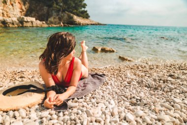 Kadın deniz sahilinde battaniyeye uzanmış fotokopi çekiyordu.
