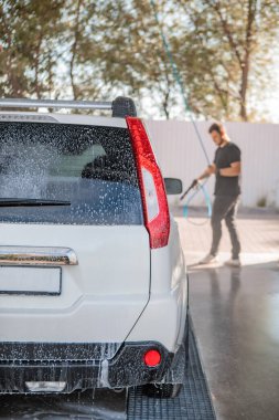 Güçlü bir adam yaz zamanı dışarıda arabasını yıkıyor.