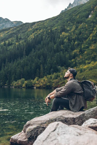 Άνθρωπος Κάθεται Στο Βράχο Μπροστά Από Λίμνη Στα Βουνά Απολαμβάνοντας — Φωτογραφία Αρχείου