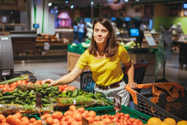 女人选择黄瓜从商店货架杂货店购物概念 — 图库照片