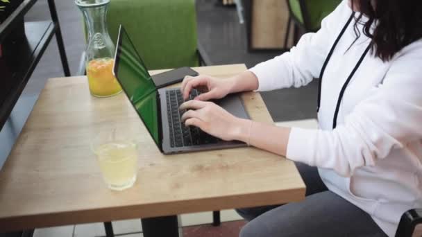 Vrouw werken in cafe op laptop toetsenbord freelancer fris drankje wit scherm — Stockvideo