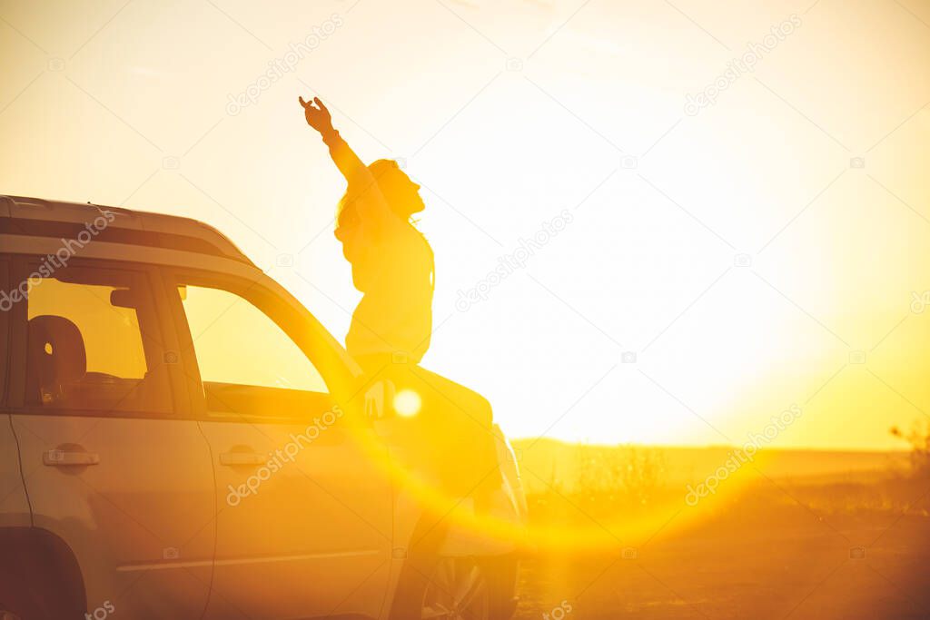 woman stop at roadside to enjoy sunset. sitting on car hood. copy space