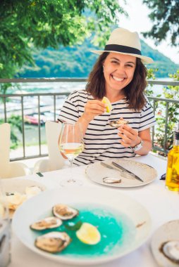 Güneşli yaz havasında açık hava restoranında istiridye yiyen bir kadın. Yaşam biçimi
