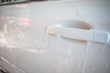 Güçlü bir adam yaz zamanı dışarıda arabasını yıkıyor.