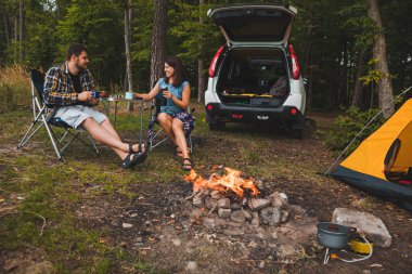 Portatif koltuklarda oturan bir çift çay içip sohbet ediyorlar. kamp yaz aktiviteleri kopyalama alanı