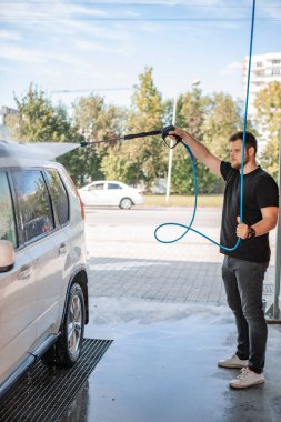 Güçlü bir adam yaz zamanı dışarıda arabasını yıkıyor.