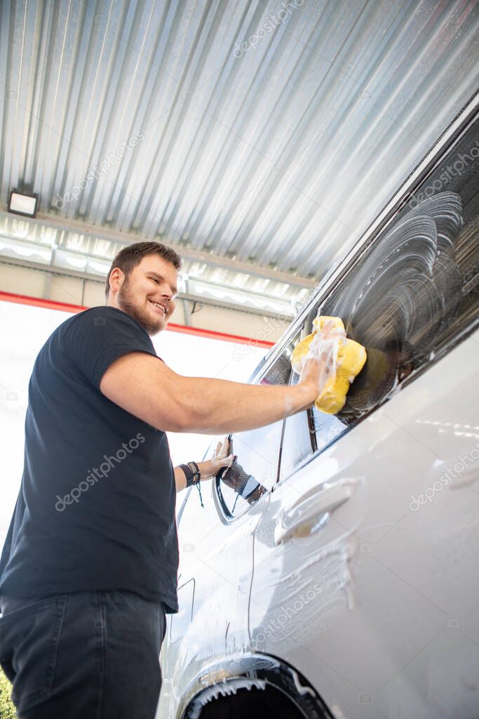 man cleaning car with yellow sponge. carwash concept. copy space