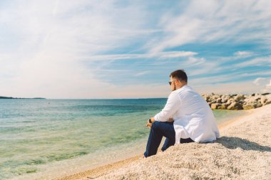 genç şık adam deniz plajında manzaranın tadını oturan. yaz tatili konsepti. kopyalama alanı