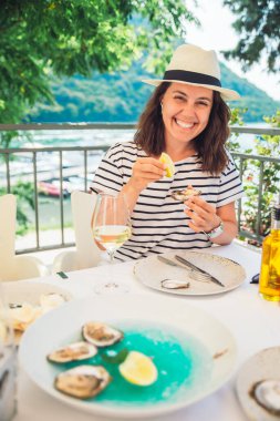Güneşli yaz havasında açık hava restoranında istiridye yiyen bir kadın. Yaşam biçimi