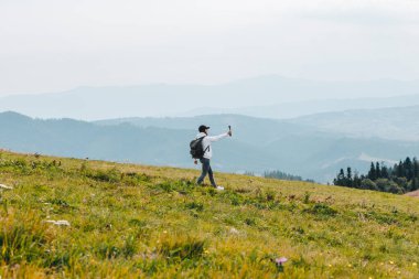 Sırt çantalı bir kadın dağda yürüyüş yapıyor. Sonbahar sezonunda kamera önünde video çekiyor.