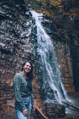 Sonbahar şelalesinin önünde gülümseyen kadın fotokopi alanı
