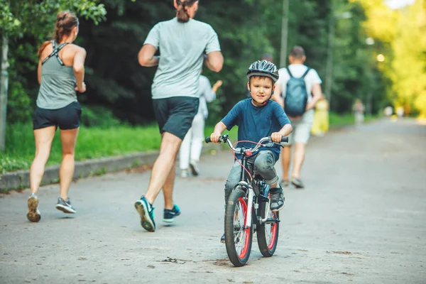 Niño Montando Bicicleta Casco Parque Público Gente Corriendo Fondo —  Fotos de Stock