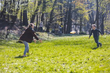 Anne güneşli baharda frizbi oynuyor. Parktaki fotokopi alanı.