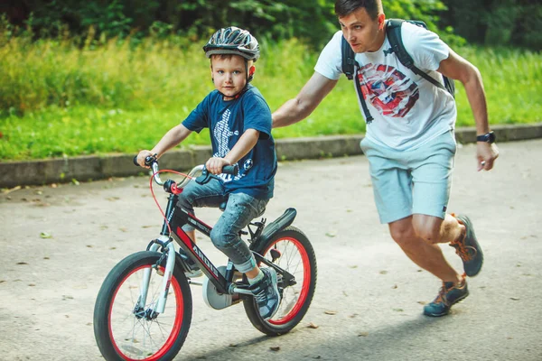 Львов, Украина - 23 июня 2019 года: отец учит сына кататься на велосипеде — стоковое фото