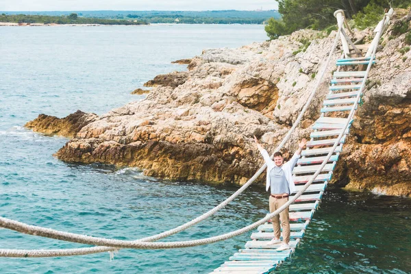 Человек идет по подвесному мосту через Адриатическое море — стоковое фото
